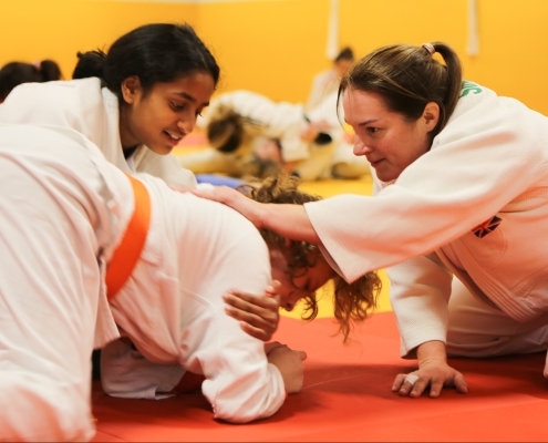 two young female judoka being coached