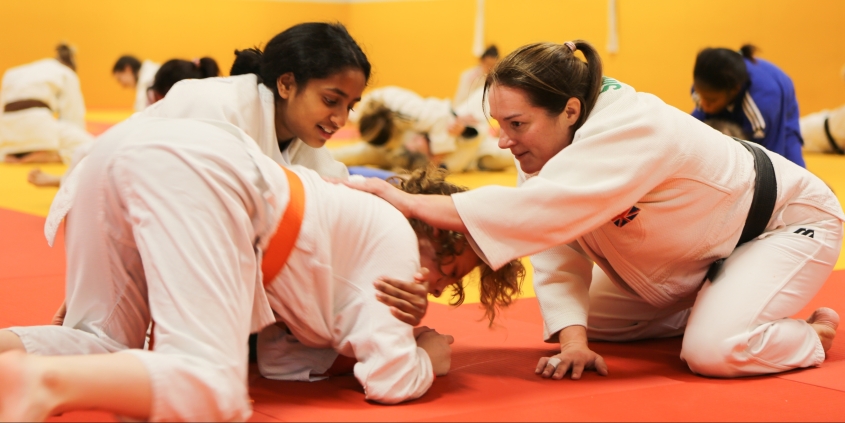 two young female judoka being coached